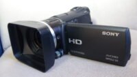 Filmadora compacta Sony HXR-MC50 preta vista de lado e tela LCD aberta